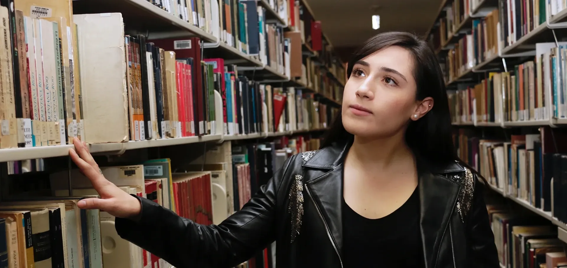 Estudiante caminando en los pasillos de la biblioteca.